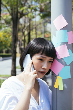 亚洲女商人黑色短发在户外打电话的画像。