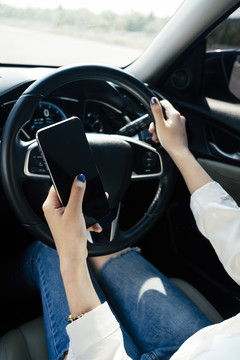 危险情况-妇女在路上开车时使用智能手机。