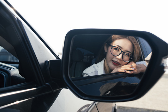 交通和车辆概念——车内戴眼镜的泰国妇女。侧镜反射。复制空间。