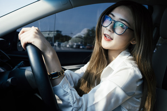 交通和车辆概念-泰国妇女戴眼镜和白衬衫驾驶汽车。