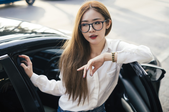 交通和车辆概念-戴眼镜的泰国妇女在黑色汽车外摆姿势。