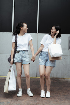 LGBTQ女同性恋者穿着休闲装手牵手一起在商场购物。