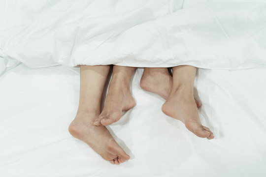 床上一对夫妇脚的特写镜头。顶视图。LGBTQ公司。