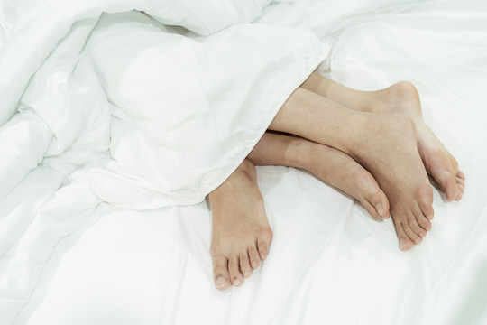 床上一对夫妇脚的特写镜头。顶视图。LGBTQ公司。