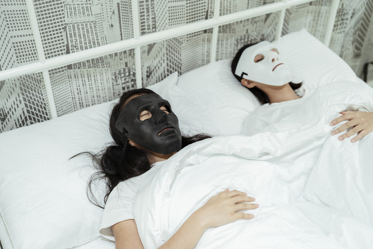 女同性恋者戴着面具睡在床上。