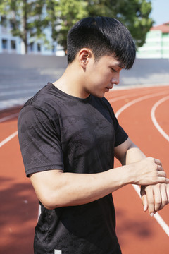 身穿黑色运动服的亚泰男子跑步场侧视图。