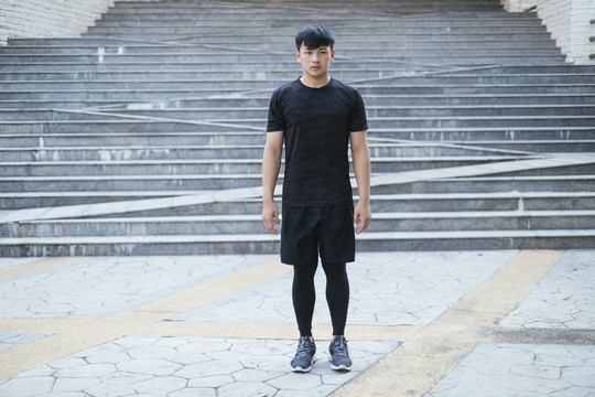 身着黑色运动服的亚泰运动男子站直的全长肖像。
