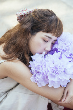 美丽的亚泰艺术家身着白色礼服睡著拥抱紫花。垂直射击。