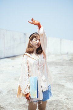 时尚写真美丽的新潮亚泰艺术家在长衬衫举行帆布户外。举手。