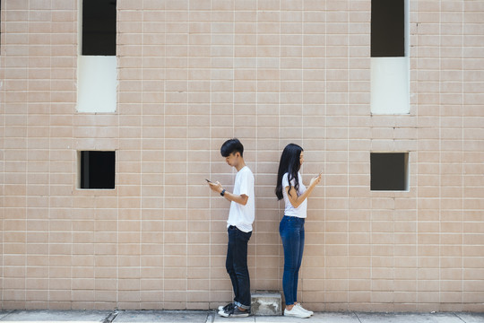一对穿着相配衣服的情侣在约会时站在墙前。