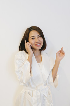 性感的泰国亚裔女子在白色衬衫上涂护肤霜在她的脸上隔离在白色背景。