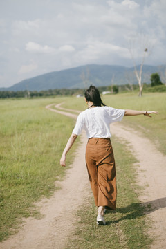 黑色马尾头发的女人穿着休闲服，戴着VR护目镜，在泥泞的草地上旅行，享受虚拟现实技术。