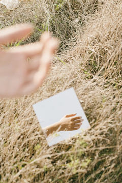 方镜落在干燥的草原上，映出女人的手。