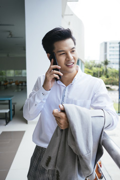 穿着白领衬衫的聪明亚泰商人在电话里面带微笑。