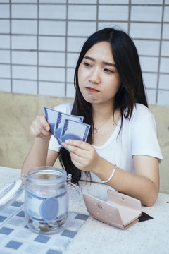 黑色长发女孩一边数，一边感激自己的省钱。