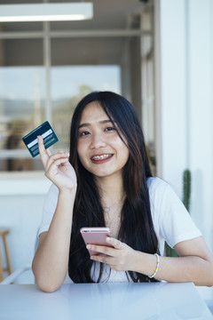 黑色长发女孩展示她用于网上购物的信用卡。