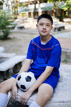 足球机器人坐在大理石长凳上拿着他的足球。垂直。