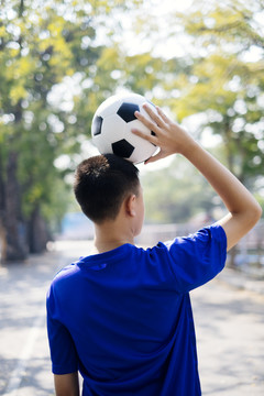 一个男孩头上顶着足球走进学校。