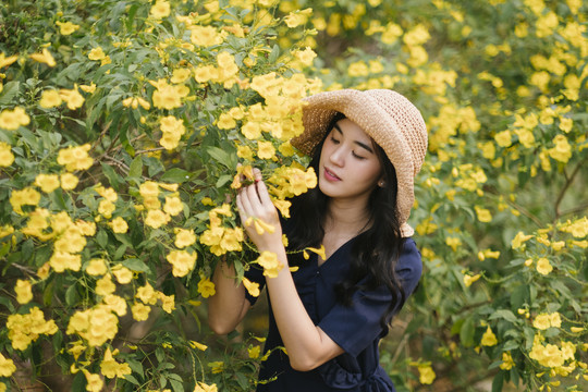 卷曲的长发女孩戴着棕色的帽子享受着黄色的花朵。