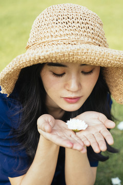 一个卷曲的长发女人在田野里的特写镜头，手里拿着一朵白花。