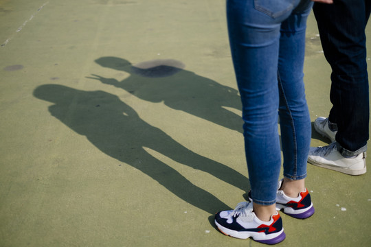 一对夫妇站在绿色地板上时的腿的剪短图像。
