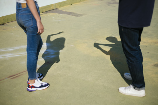 一对夫妇站在绿色的地板上，享受着他们的影子时，他们的腿的剪短图像。