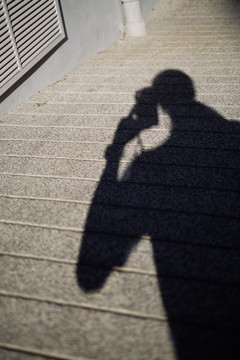 摄影师的影子家伙拿着相机走在斜坡上的小路上。