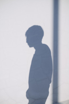 一个男人的影子在白墙上用杆子。