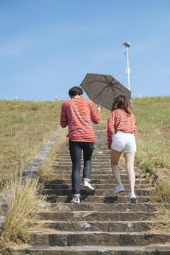 一对年轻夫妇手里拿着雨伞一起走上石阶。
