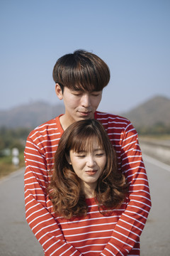 一个男人抱着他女朋友的背，他们站在山景大道上。