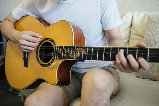 在客厅里的沙发上玩原声吉他的特写镜头。