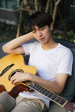 帅气的年轻泰国吉他手和原声吉他手的肖像。