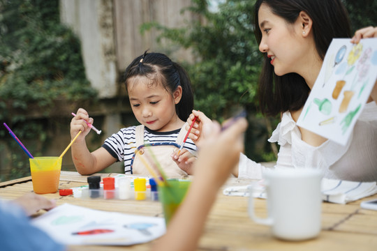 两个亚洲姐妹一起在户外画水彩-家庭活动。