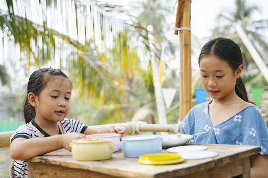 两个亚洲小孩在乡下的木桌上用食物盒或平托吃午餐。