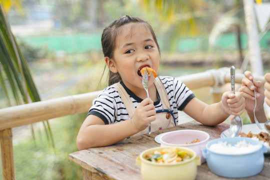 在乡下，可爱的小女孩用叉子吃炸虾的特写镜头。