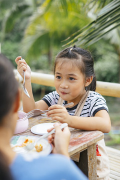 那个小女孩和家人在乡下农场吃饭。在大自然中进食。