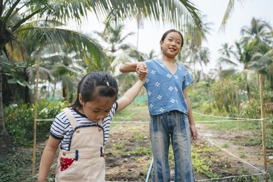 快乐的两个亚洲小女孩手牵着手走在泰国农村的有机农场。