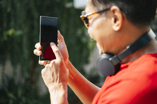 当老人从应用程序中选择音乐时，他手里拿着一个不规则的智能手机。