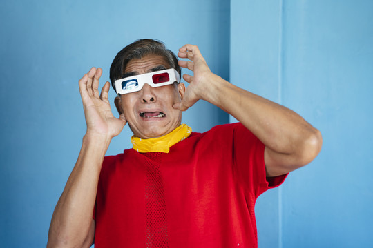 穿红色t恤的老人戴着3D眼镜，他惊讶地发现电影里的东西都能通过显示屏。