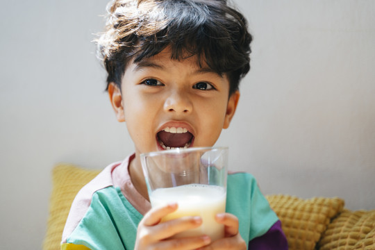 小男孩快乐地喝着透明玻璃杯里的牛奶。