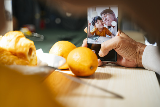 爷爷和孙子在智能手机的摄像头里，一边吃早餐一边自拍。