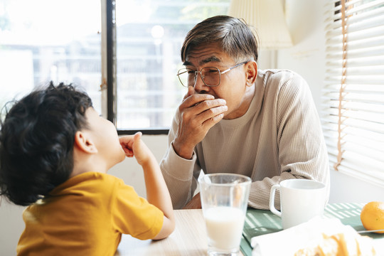 孙子在早餐时告诉爷爷他的牙齿。