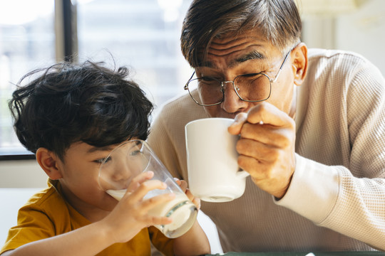 小男孩和爷爷一起喝饮料，他早上喝牛奶，爷爷喝咖啡。