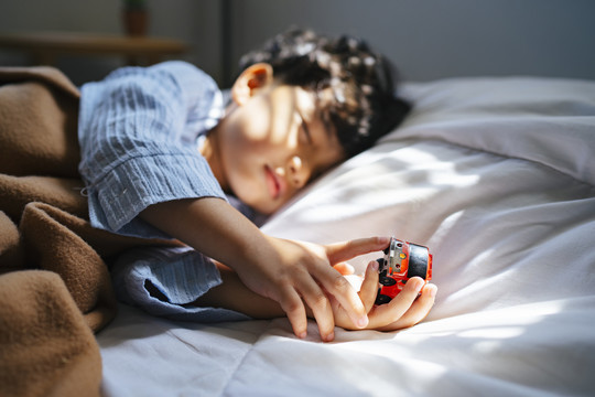男孩中午睡觉时手里拿着一个汽车玩具的剪影。