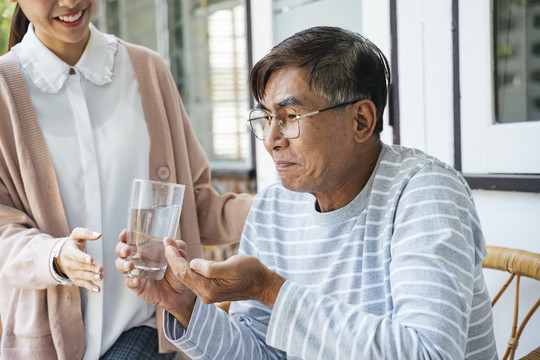 这位老人从私人护士那里拿药片治头痛。