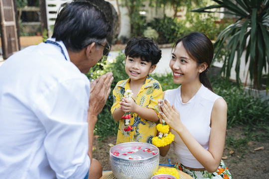 泰国家庭日的传统活动是母亲用茉莉花环将儿子的双手按在胸前，以此来教儿子对爷爷表示敬意。