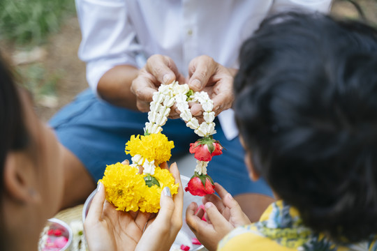 在一年一度的传统节日里，老人接受女儿和孙子送的花环时手的剪影。