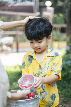 在每年的传统节日里，小男孩把花水倒在妈妈的手上。