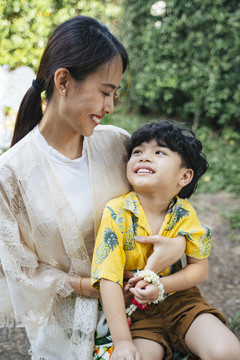 小男孩坐在妈妈的腿上，妈妈用爱拥抱着他。