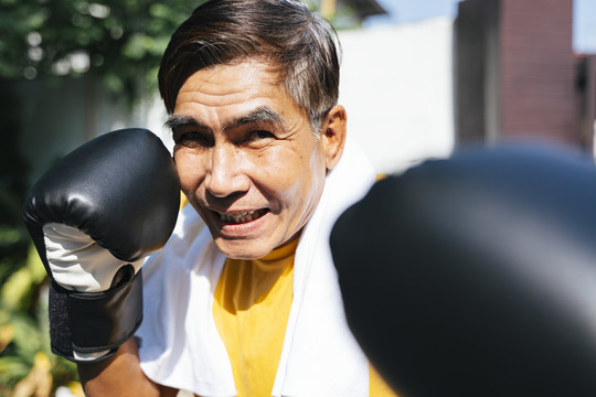 在阳光明媚的日子里，老人一个人在家里接受拳击训练。